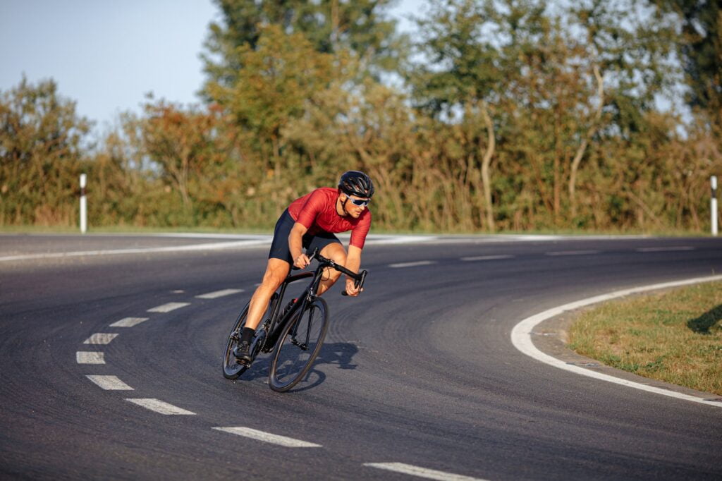 Strong athlete riding bike with high speed on road